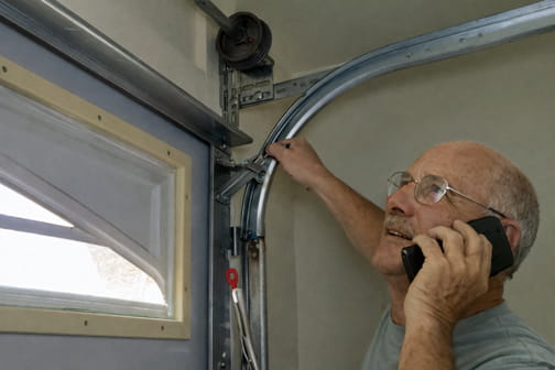 A customer checking garage door rail for looseness while on the phone with Larry from Same Day Garage Door Repair
